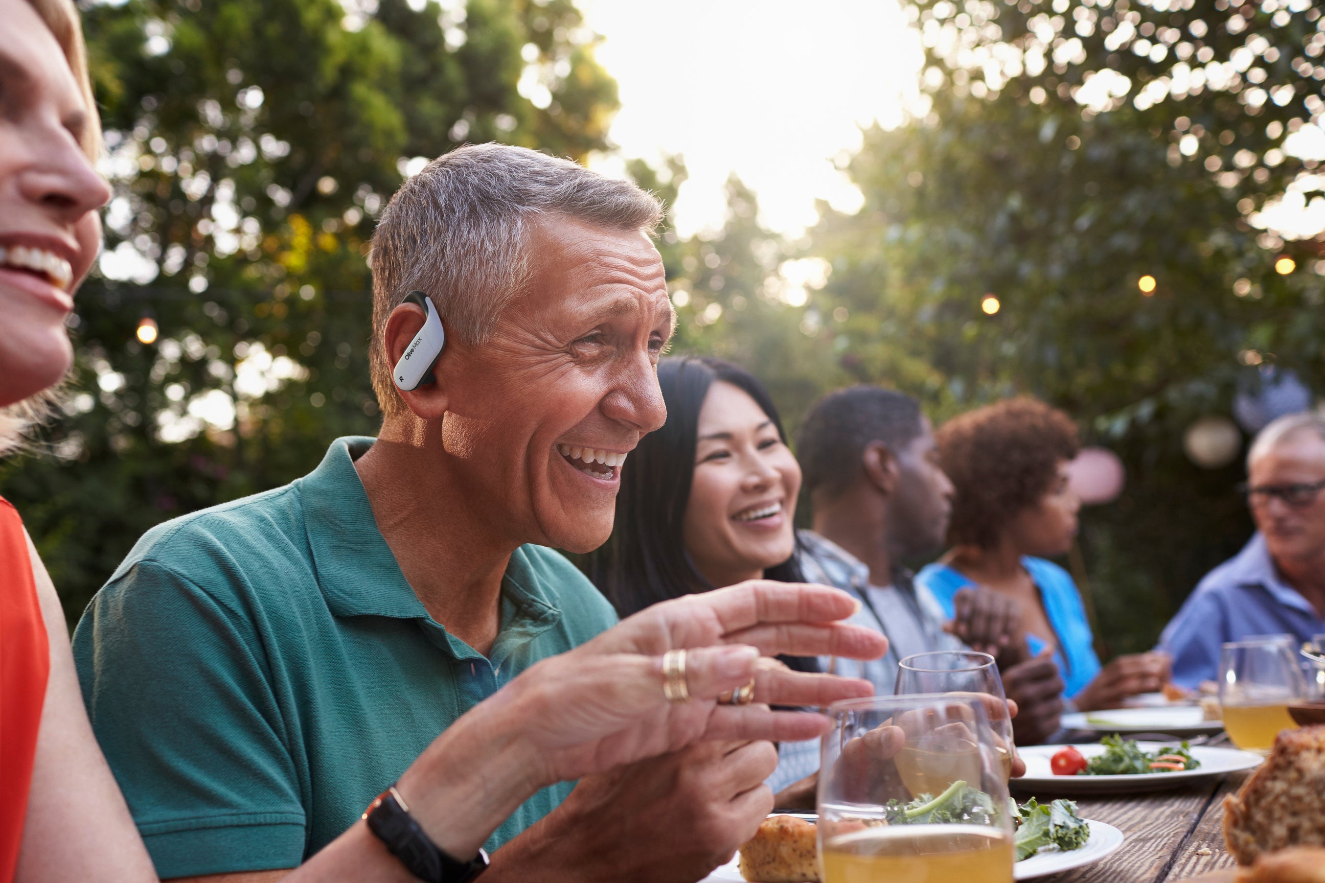 a man with hearing aid is smiling during having a meal