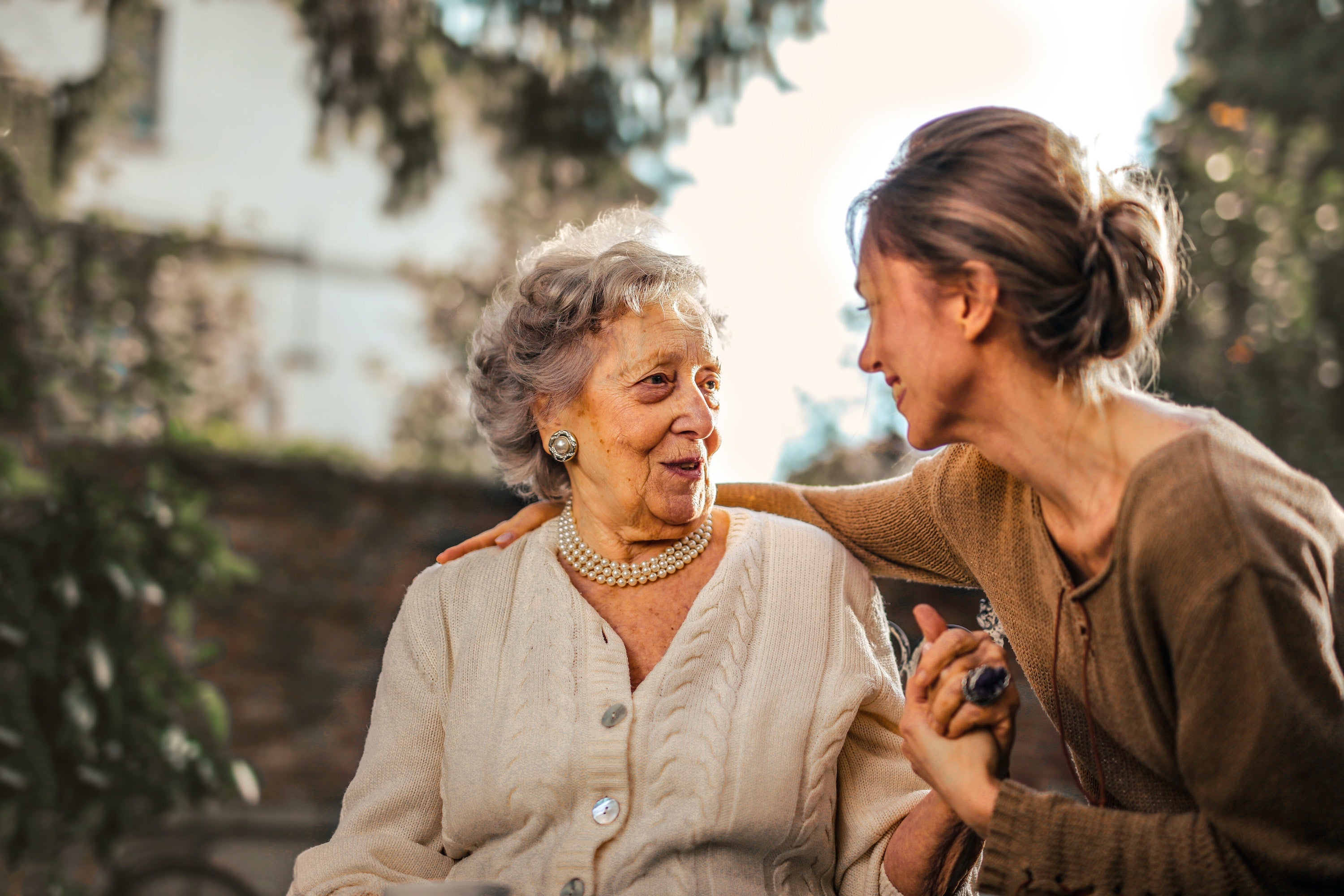 middle aged woman talking to older woman with hearing aid