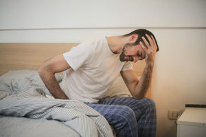 man in pyjamas getting out of bed struggling to hear