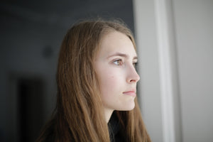woman looking out a window thinking about hearing aid alternatives