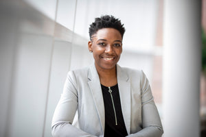 woman in grey lapel suit looking at camera